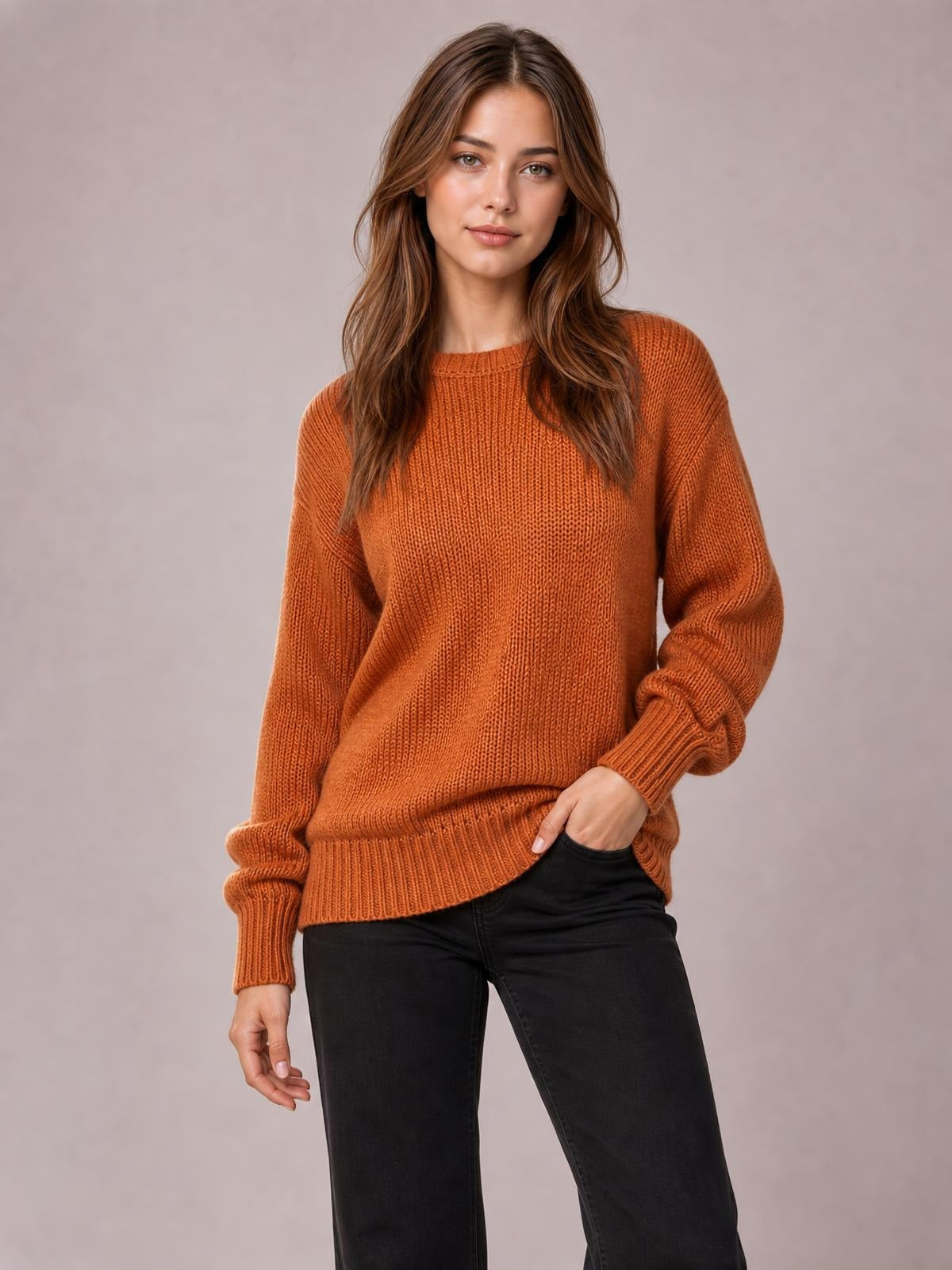 Model poses in an orange solid-color ribbed sweater with drop shoulders, crew neckline, relaxed silhouette, and ribbed cuffs and hem.