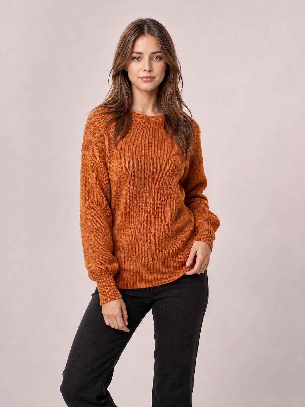 Model wears a rust-orange solid color ribbed trim drop shoulder sweater with a relaxed silhouette, long sleeves, and ribbed cuffs and hem.