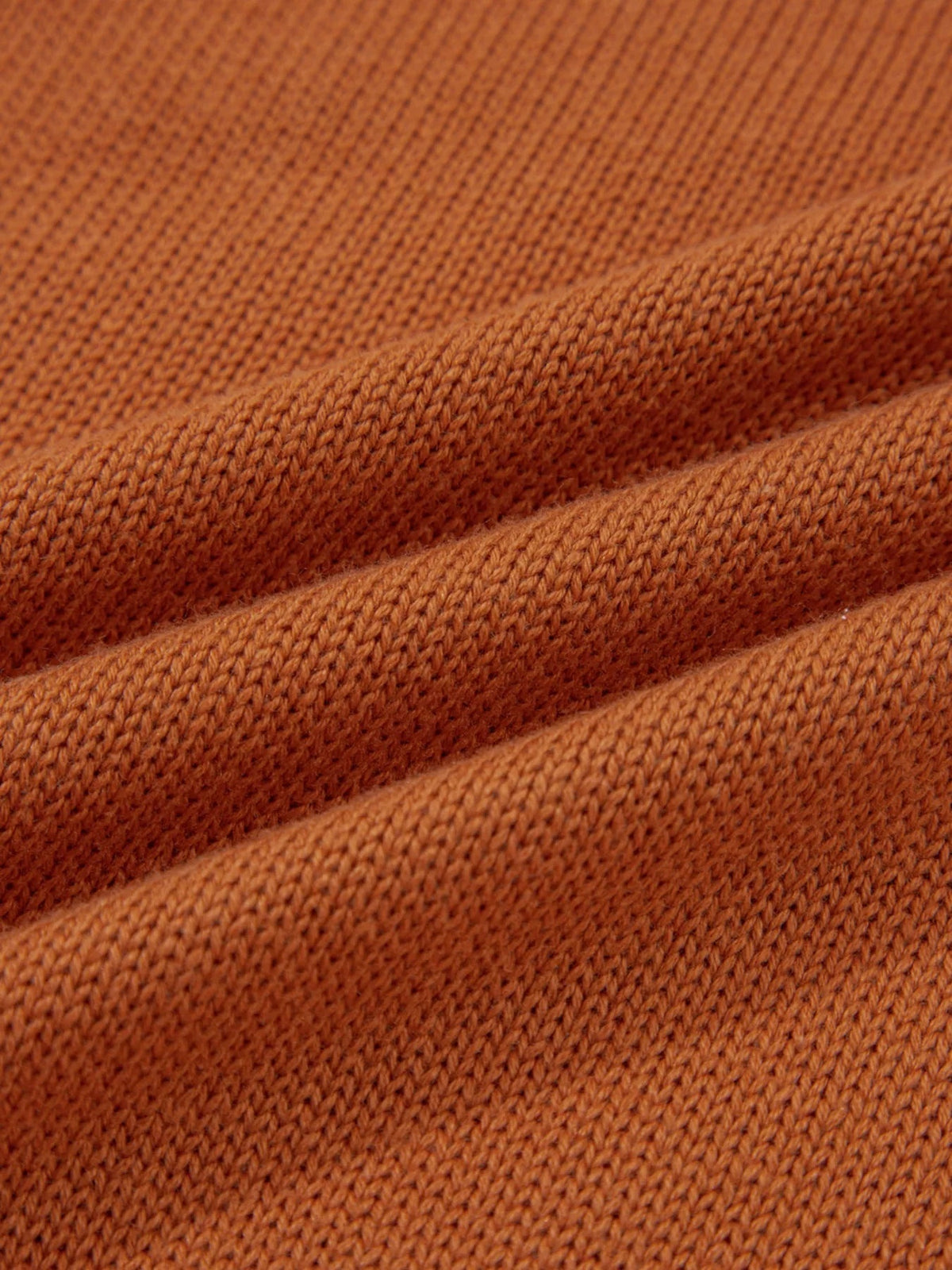 Close-up of a solid warm brown sweater showing its soft knit texture and raised ribbed trim construction.