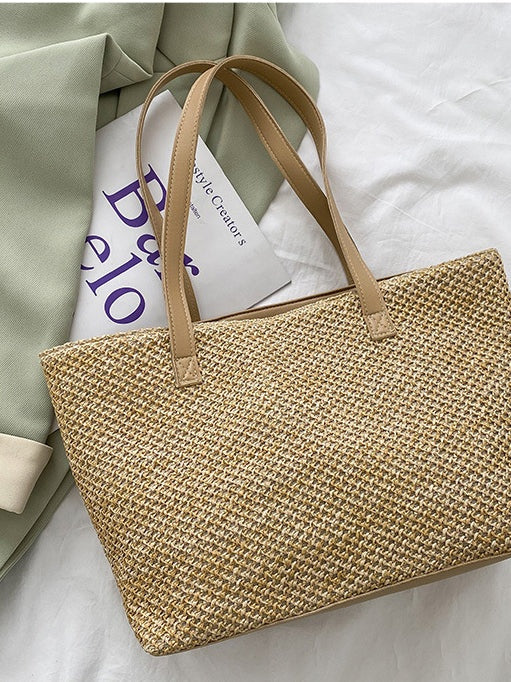 Medium solid-color woven tote bag in natural tan with a structured rectangular silhouette, textured open weave, and long stitched shoulder straps.