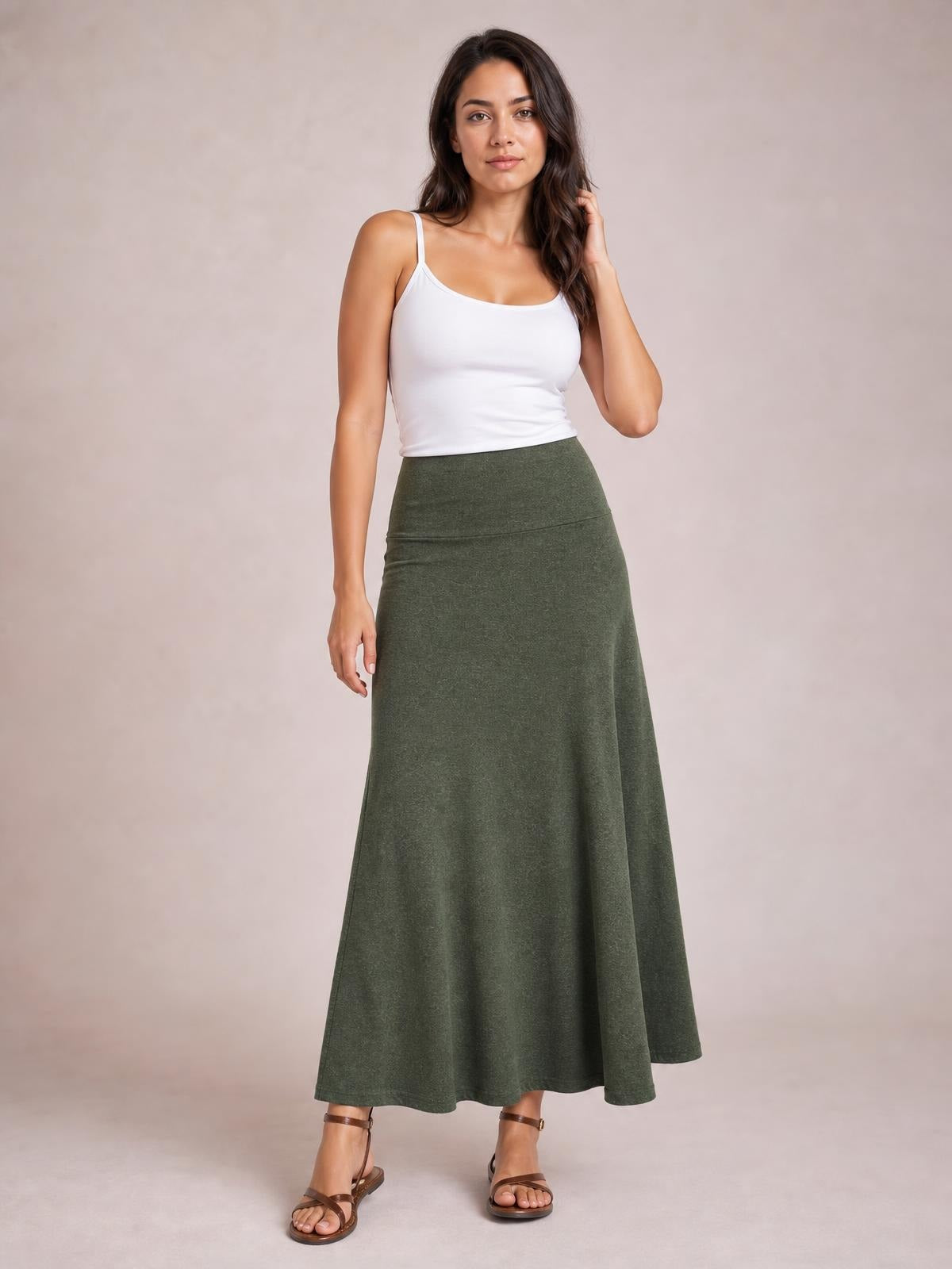 Standing model poses with one hand in her hair, wearing a solid olive-green elastic-waist maxi skirt with a smooth waistband and flowing A-line silhouette.