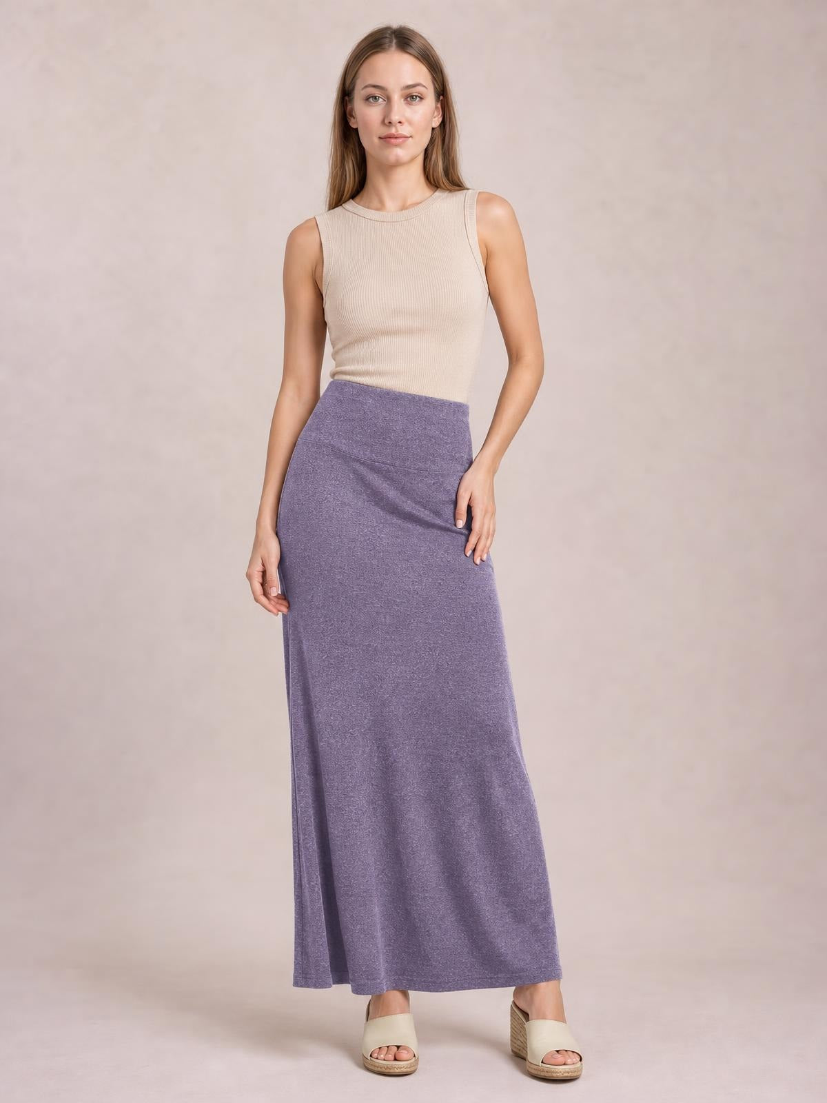 Model poses in a solid lavender elastic waist maxi skirt with a smooth waistband and long, flowing silhouette.