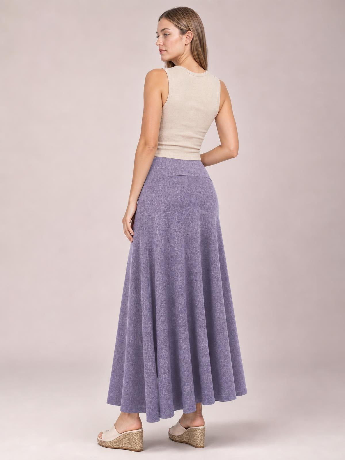A model poses in a three-quarter back view wearing a lavender solid elastic-waist maxi skirt with a wide waistband and flowy, full-length A-line silhouette.