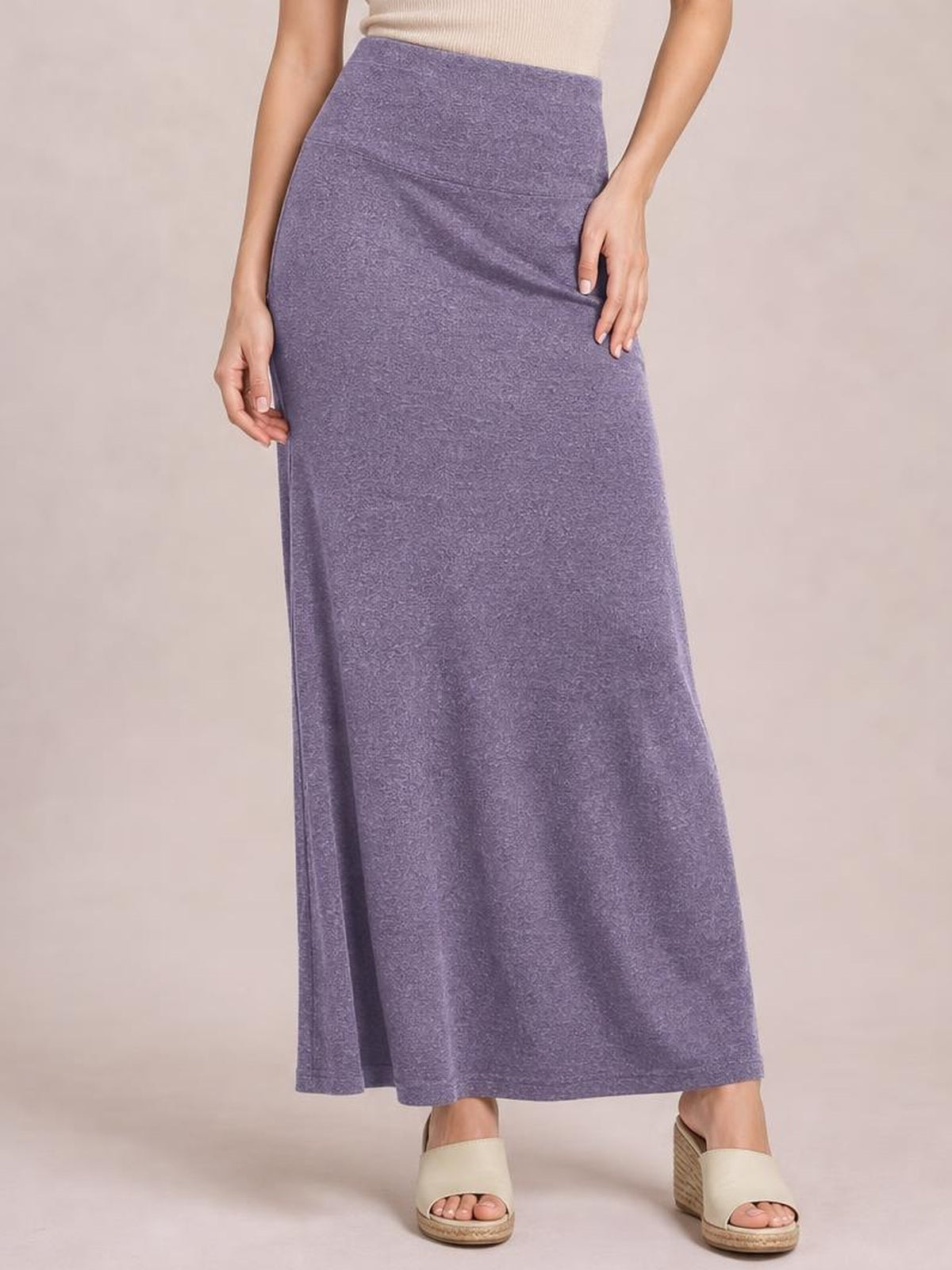 Model stands in a lavender solid maxi skirt with an elastic waist, smooth construction, fitted hip, and long flowy silhouette.