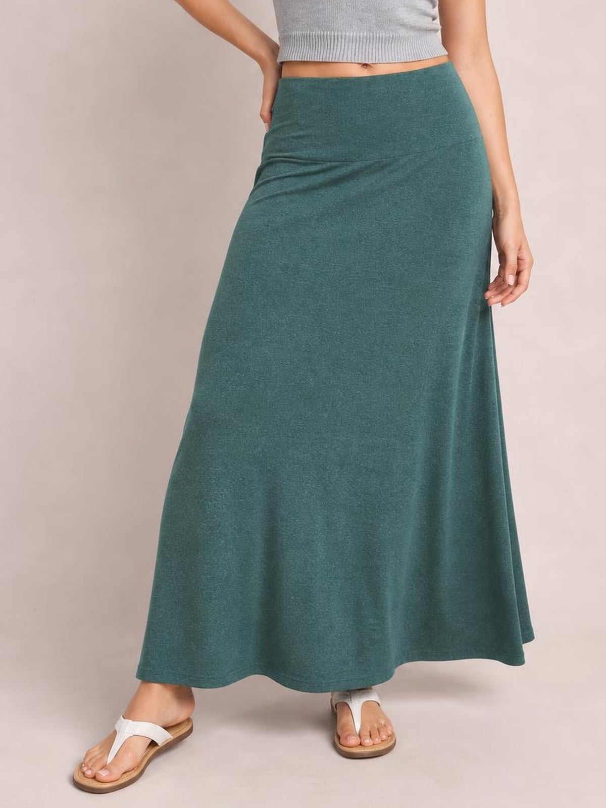A model poses in a solid teal elastic-waist maxi skirt with a smooth, flowy A-line silhouette and gently draped construction.
