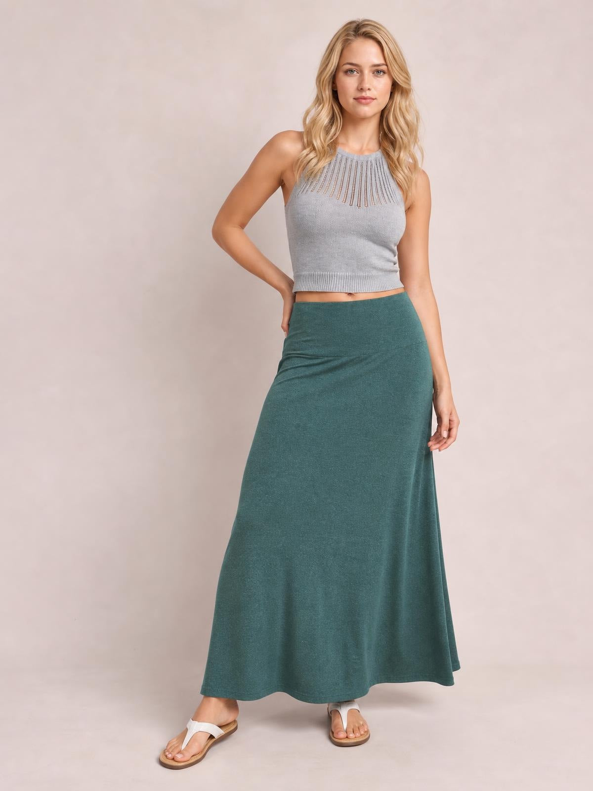 Model poses in a solid teal elastic-waist maxi skirt with a flowy, full-length silhouette and softly draped construction.