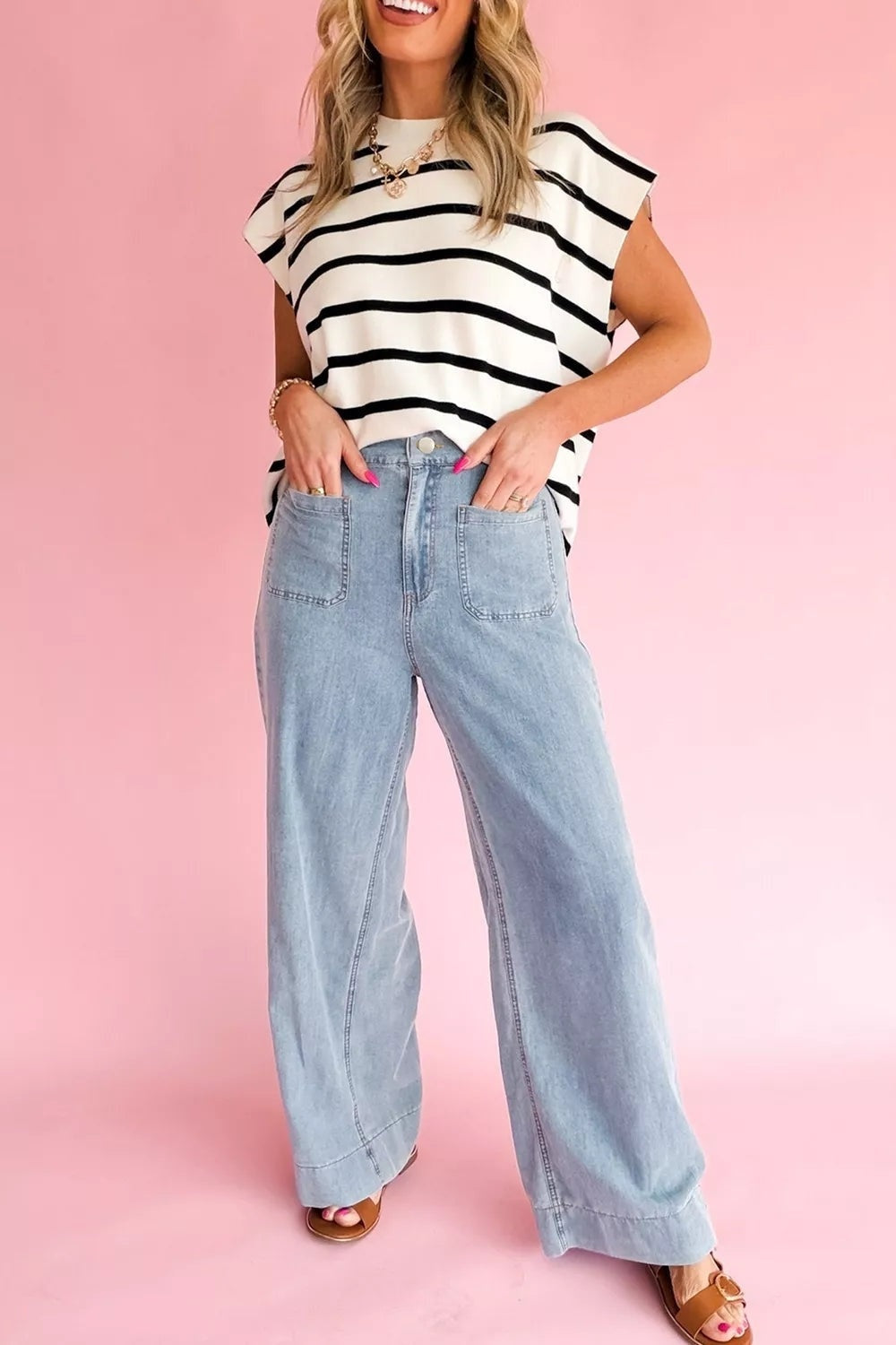 Model poses with hands in the pockets of light-wash, full-length jeans featuring a high waist, wide-leg silhouette, and visible front pocket construction.