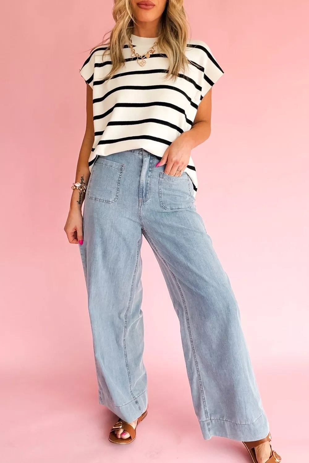 Model wearing light-wash full-length jeans with a relaxed wide-leg silhouette, front patch pockets, visible seams, and cuffed hems.
