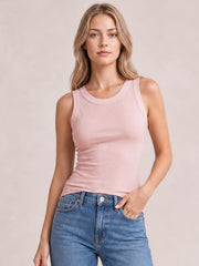 Model wearing a solid pink round neck tank with wide shoulder straps and a fitted, slightly stretchy silhouette, paired with blue jeans.