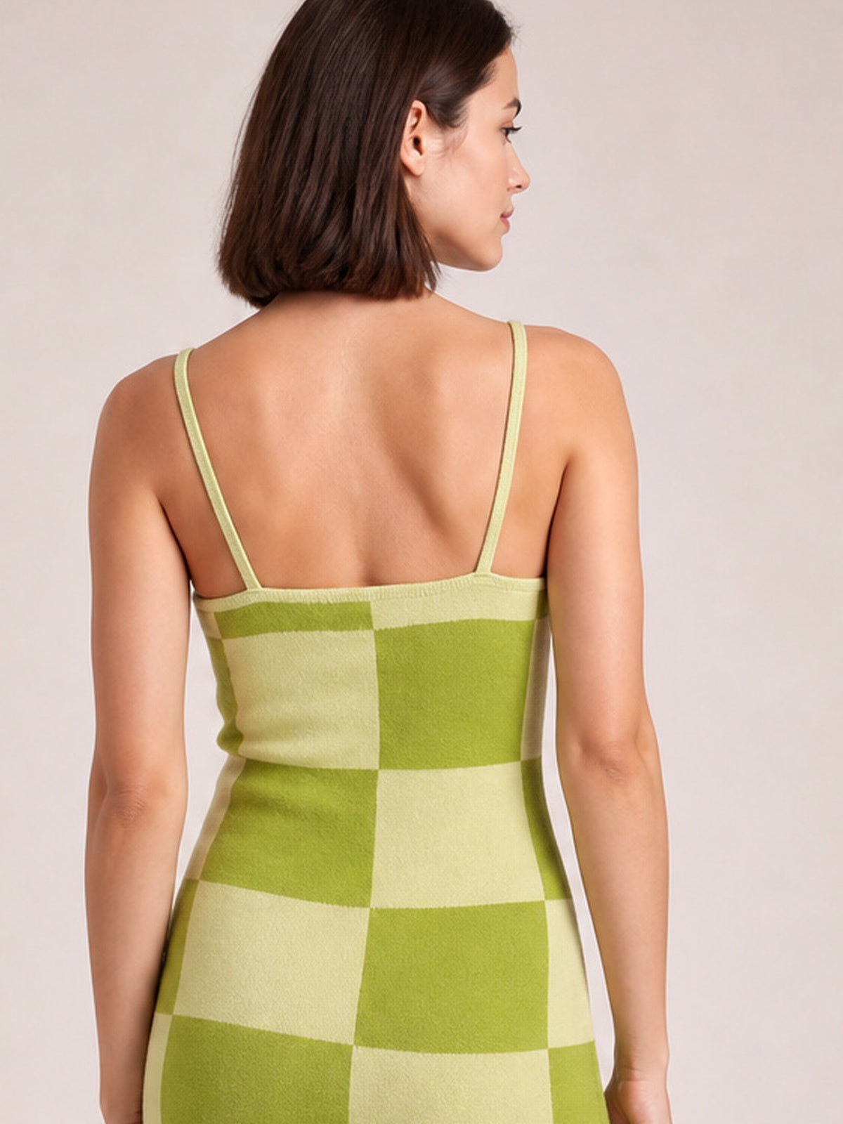 Model shown from behind wearing a green and light-lime checkerboard maxi sweater dress with slim spaghetti straps and a fitted, stretchy silhouette.