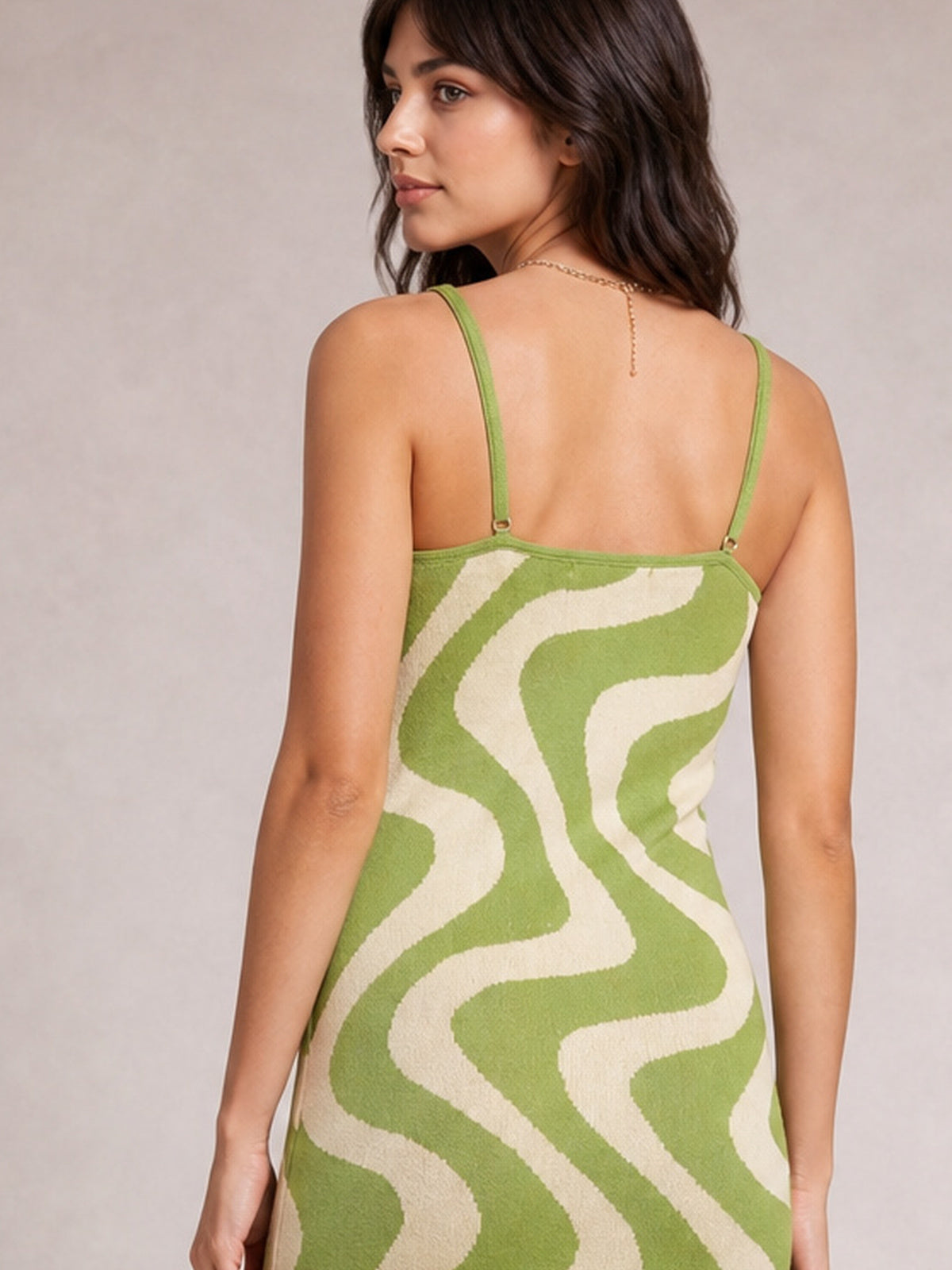 Model shown from the back in a green and cream patterned spaghetti strap maxi sweater dress with a fitted, streamlined silhouette and adjustable shoulder straps.