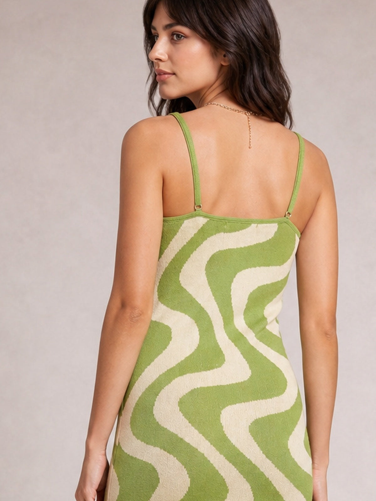 Model shown from the back in a green and cream patterned spaghetti strap maxi sweater dress with a fitted, streamlined silhouette and adjustable shoulder straps.