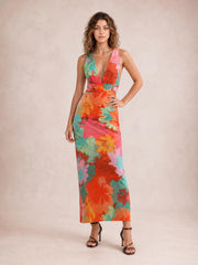 Model poses in a vibrant floral printed plunge maxi dress with tied waist, wide shoulder straps, and a slim, floor-length silhouette.