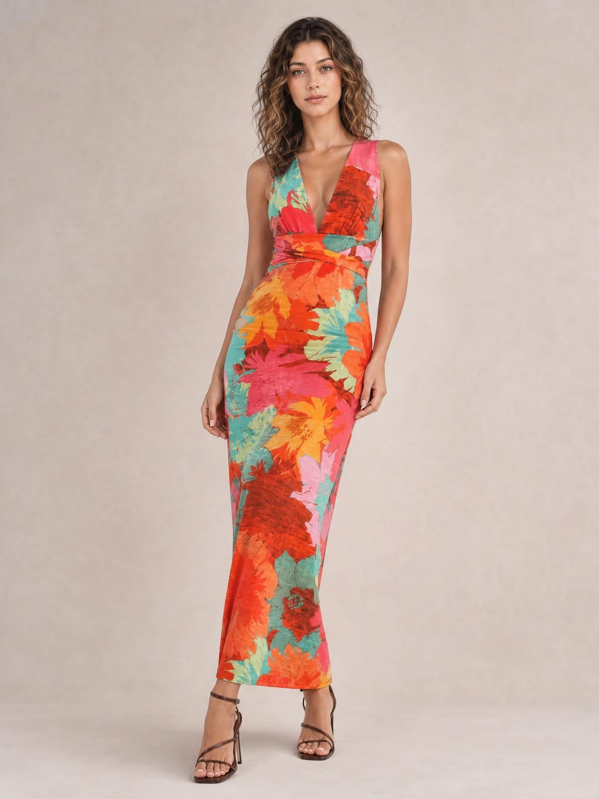 Model standing in a vibrant multicolor printed plunge maxi dress with wide shoulder straps, a fitted silhouette, and a floor-length hem.