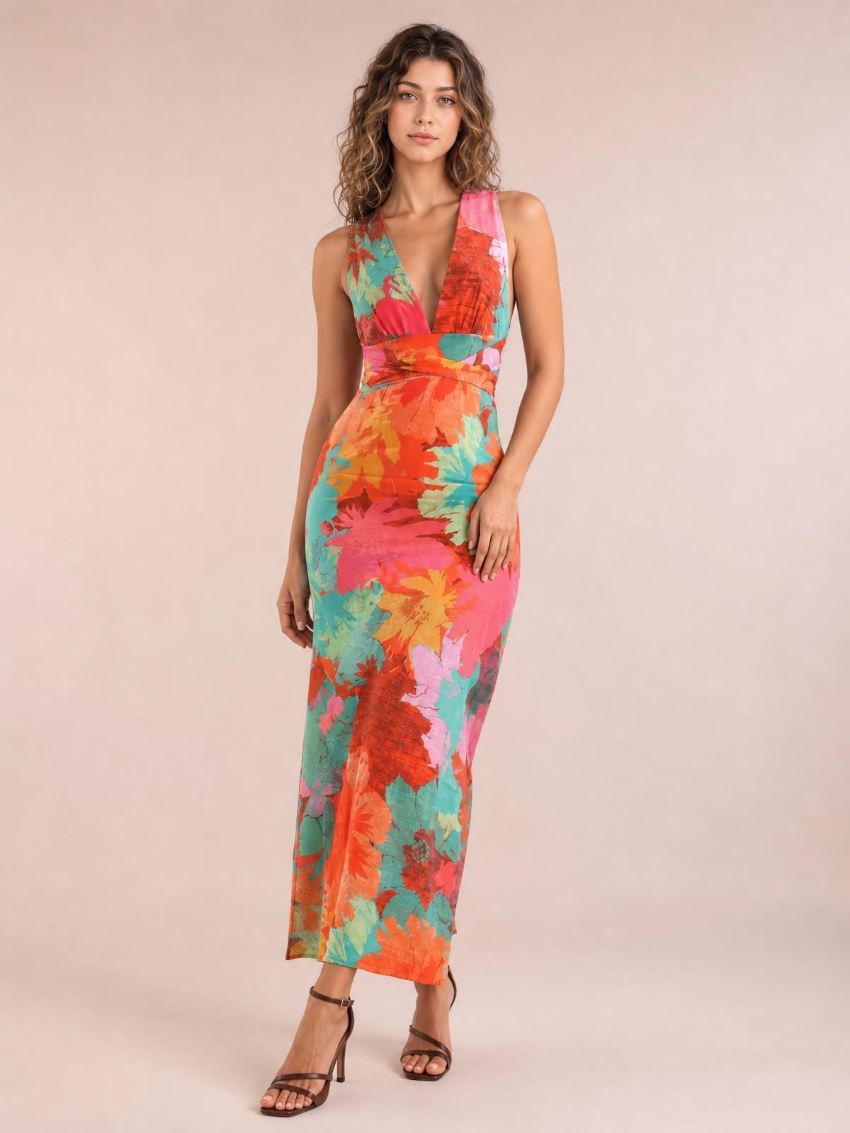 A model stands in a fitted multicolor floral printed plunge maxi dress with wide shoulder straps, a wrapped tied waist, and a long straight silhouette.