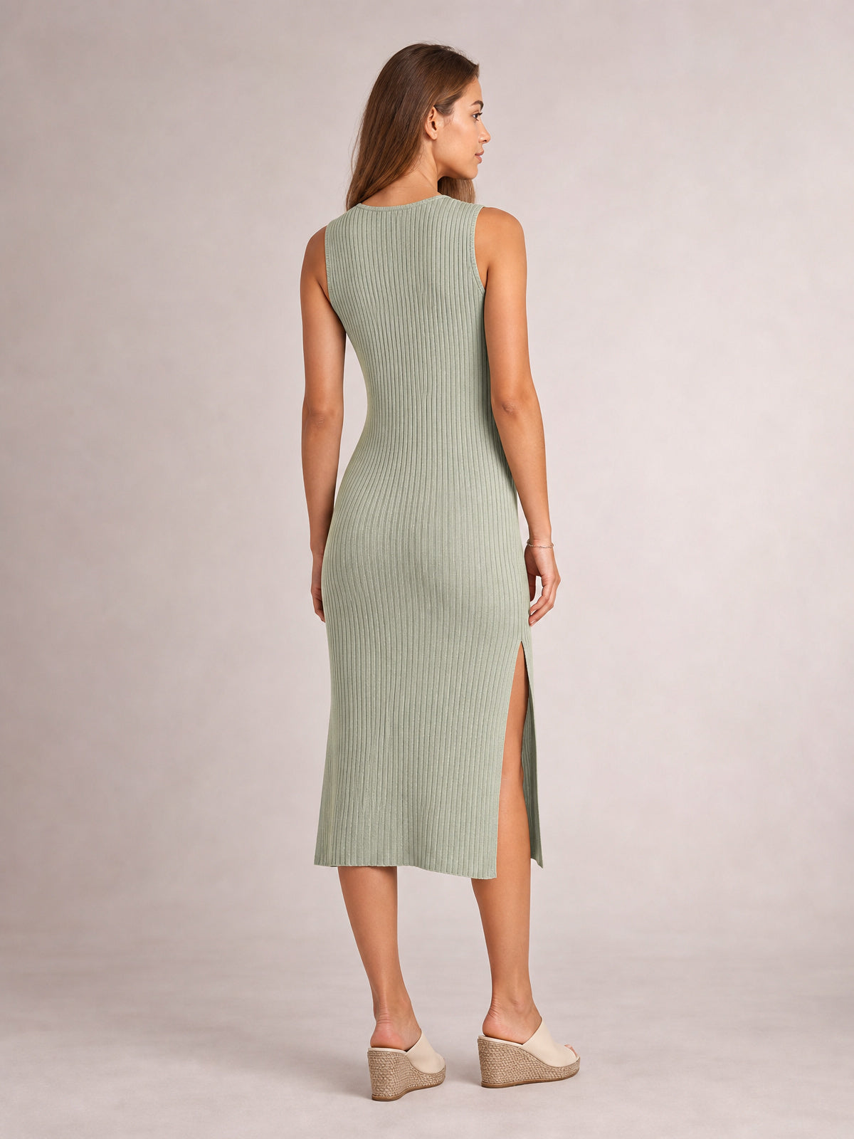 Model shown from behind in a sage green sleeveless midi dress with a round neck, body-skimming silhouette, vertical ribbed texture, and side split.