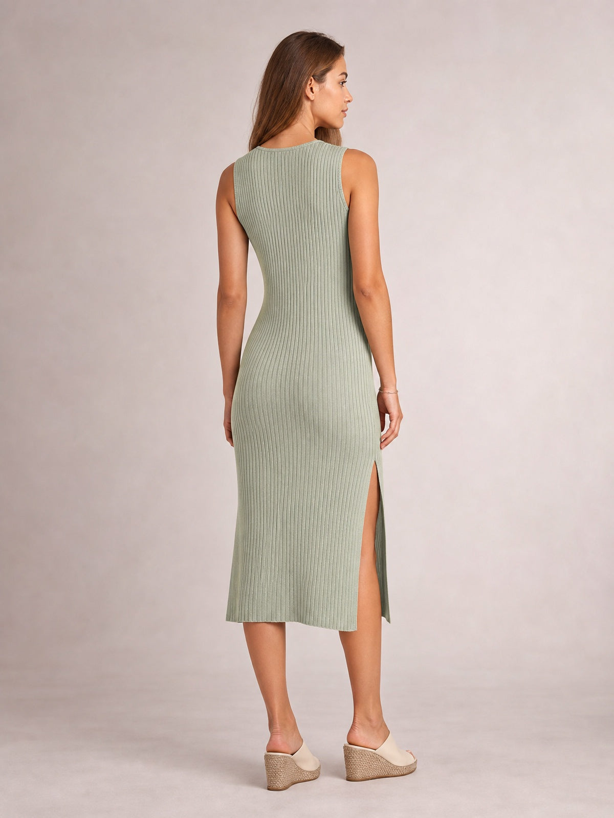 Model shown from behind in a sage green sleeveless midi dress with a round neck, body-skimming silhouette, vertical ribbed texture, and side split.