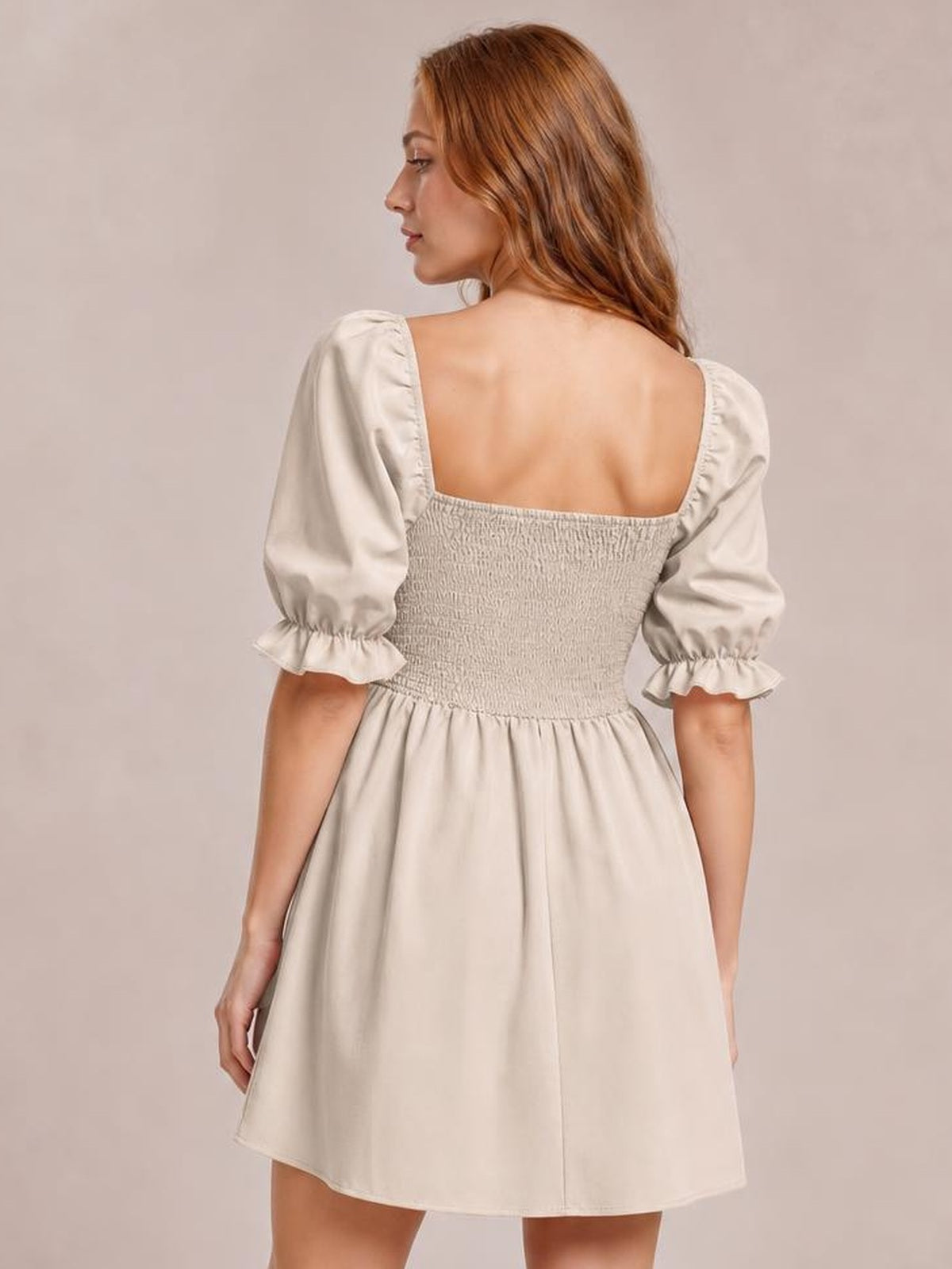 A model faces away in a cream square-neck mini dress with puffed flounce sleeves, a smocked back bodice, and a relaxed A-line silhouette.