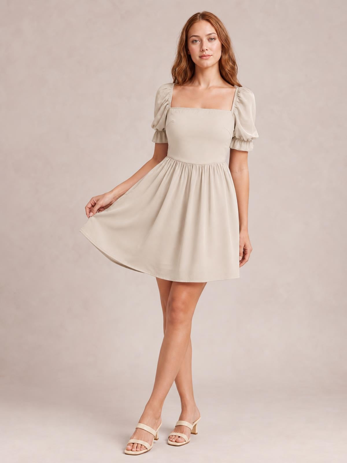 Model poses in a cream square-neck mini dress with puffed flounce sleeves, a fitted bodice, gathered waist, and softly flared skirt held out to one side.