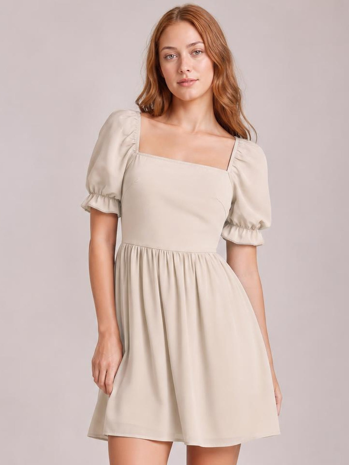 Model stands in a cream square-neck mini dress with flounce-trimmed puff sleeves, fitted bodice, gathered waist, and a softly flared skirt.