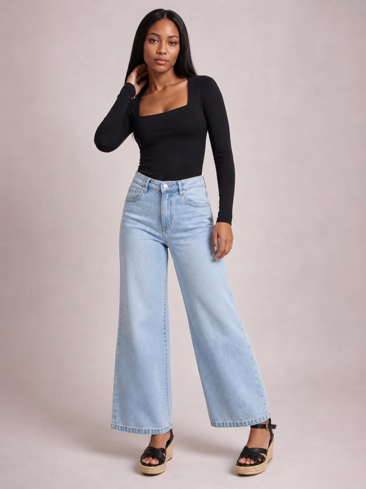 Model poses in a fitted black square neck long sleeve T-shirt with a smooth opaque finish and moderate stretch.