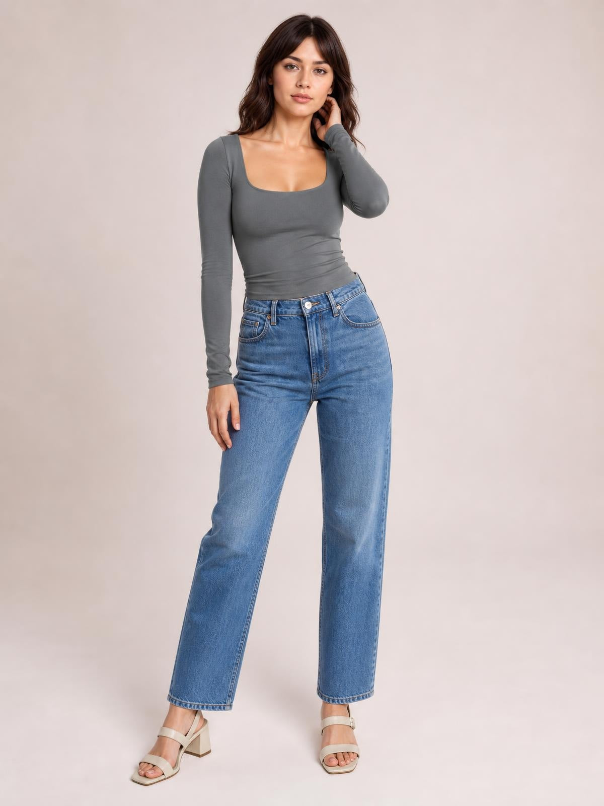 Model wears a gray square neck long sleeve T-shirt with a fitted silhouette and ruched waist, posing with one hand near her hair.