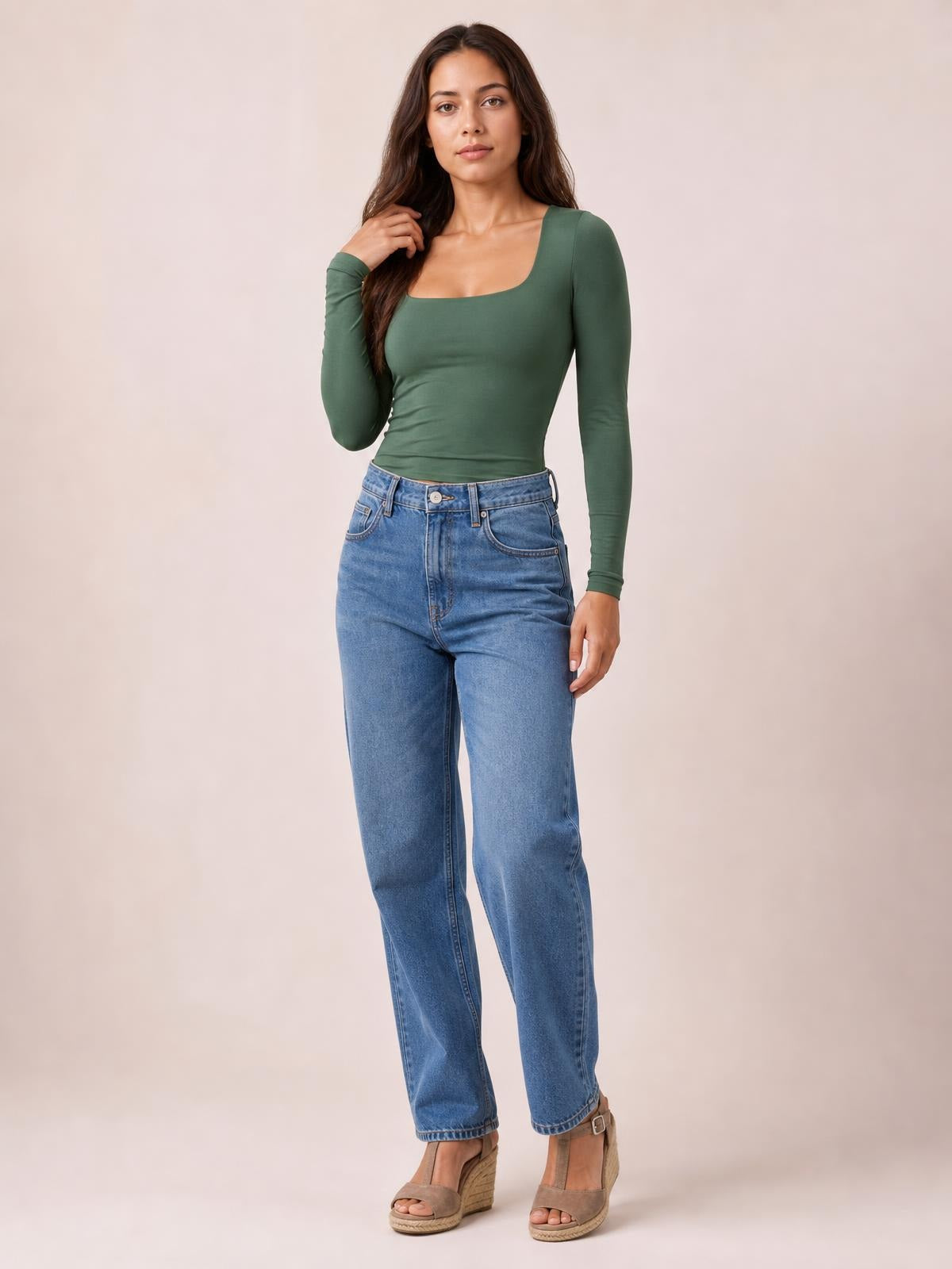 Model poses in a fitted olive green square neck long sleeve T-shirt with a smooth basic silhouette, paired with blue jeans.