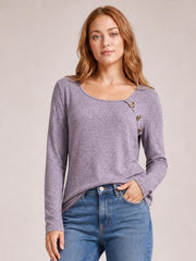 A model poses in a lavender long sleeve T-shirt with a wide square neckline, subtle textured pattern, fitted silhouette, and decorative button detail.