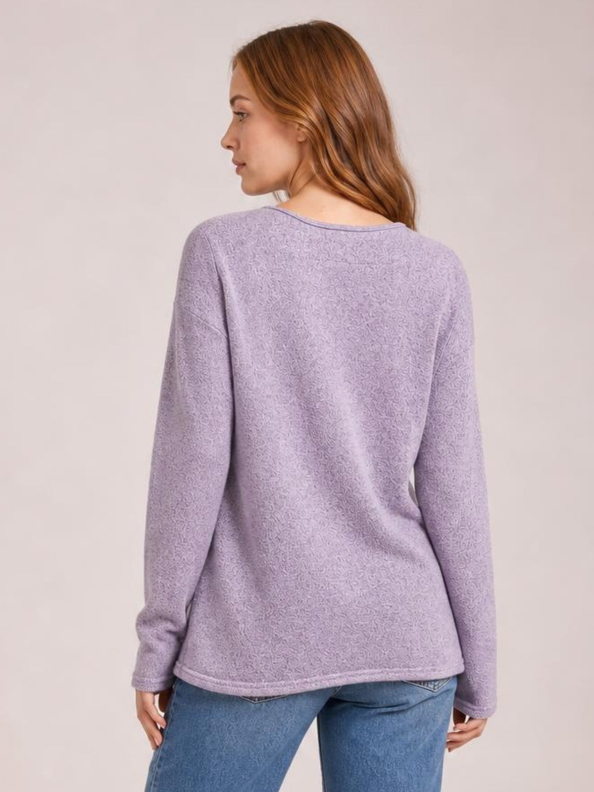 Model shown from behind wearing a lavender long sleeve T-shirt with a relaxed straight silhouette, textured fabric, and neatly finished hem and cuffs.