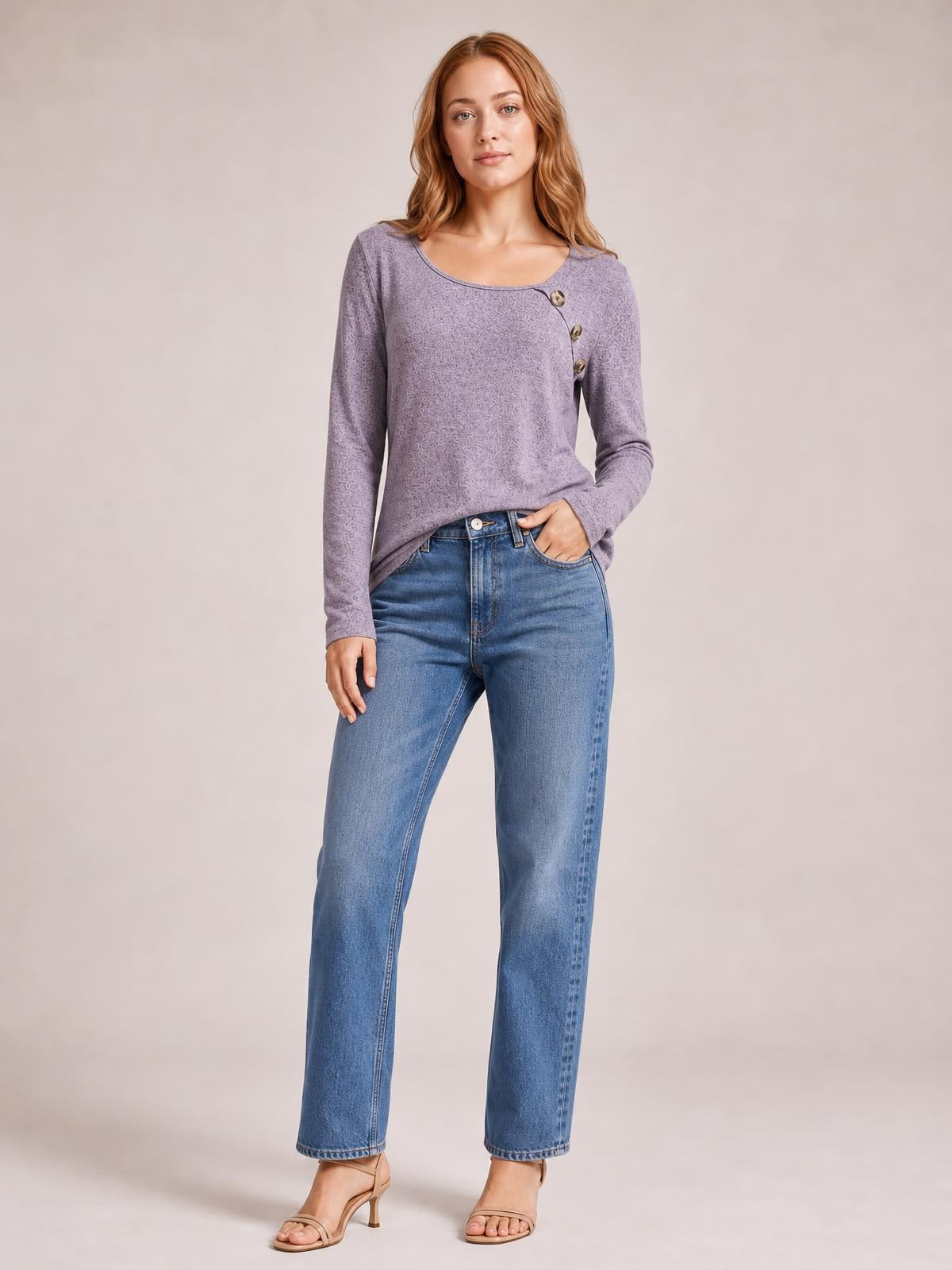 A model wears a lavender square-neck long-sleeve T-shirt with a fitted silhouette, subtle texture, and diagonal button detail, styled with jeans.