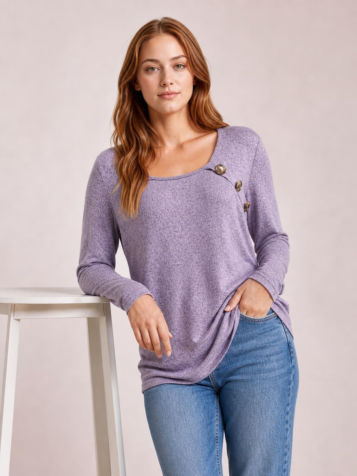 Model leans beside a table in a lavender square-neck long sleeve T-shirt with a relaxed silhouette, subtle texture, and button accents at the shoulder.