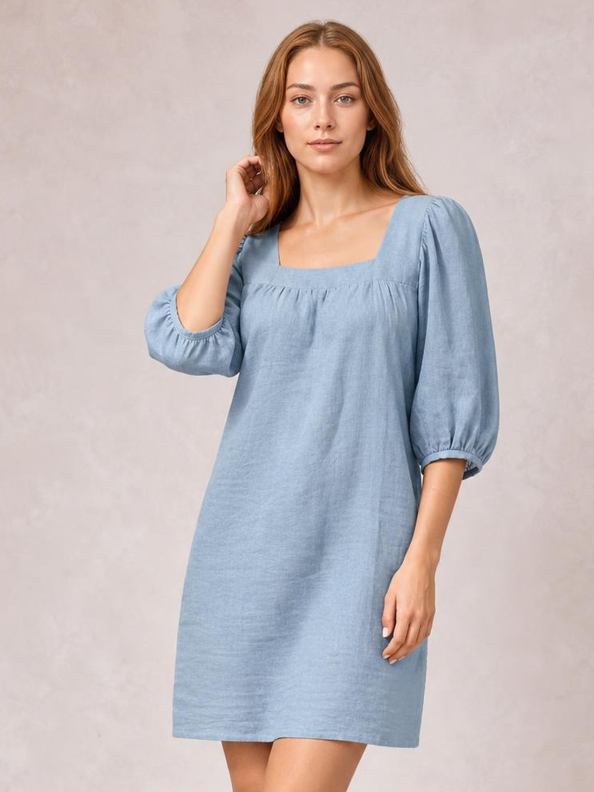 Model poses in a relaxed light blue mini dress with a square neckline, puff sleeves, gathered seam detail, and a straight loose silhouette.