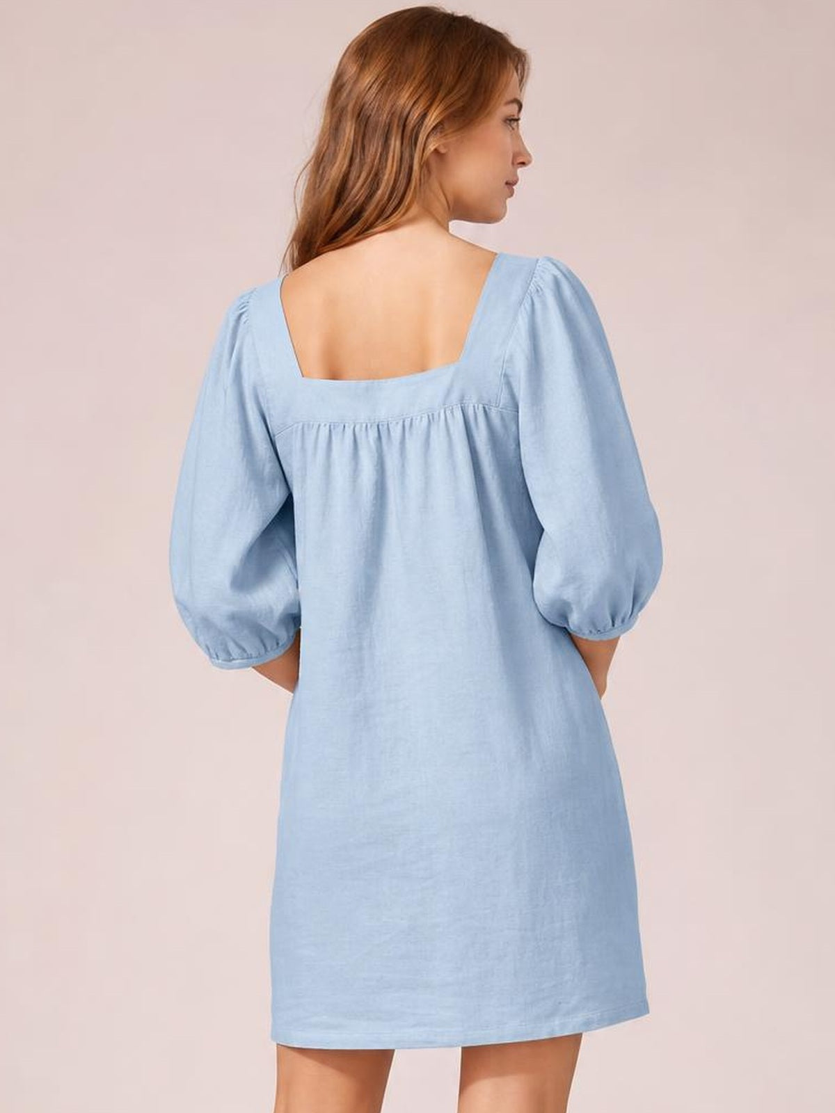 Model shown from behind in a light blue square-neck mini dress with puff sleeves, gathered seam detail, relaxed silhouette, and a straight hem.