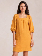 Front-facing model wears a mustard square-neck puff sleeve mini dress with seam detailing, a relaxed straight silhouette, and sleeves gathered at the cuffs.