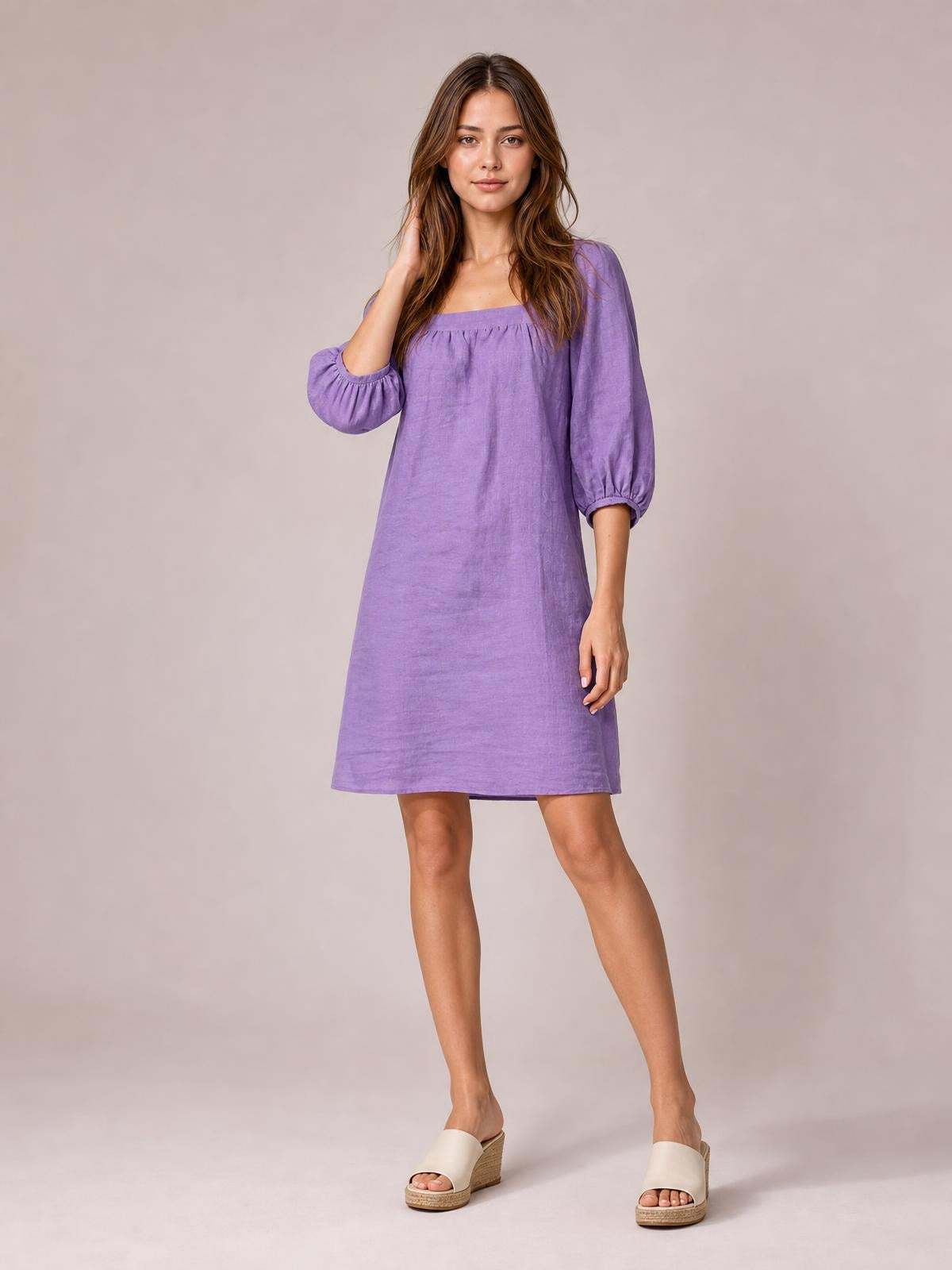 Model poses in a relaxed purple mini dress with a square neckline, gathered puff sleeves, seam detailing, and a straight silhouette.