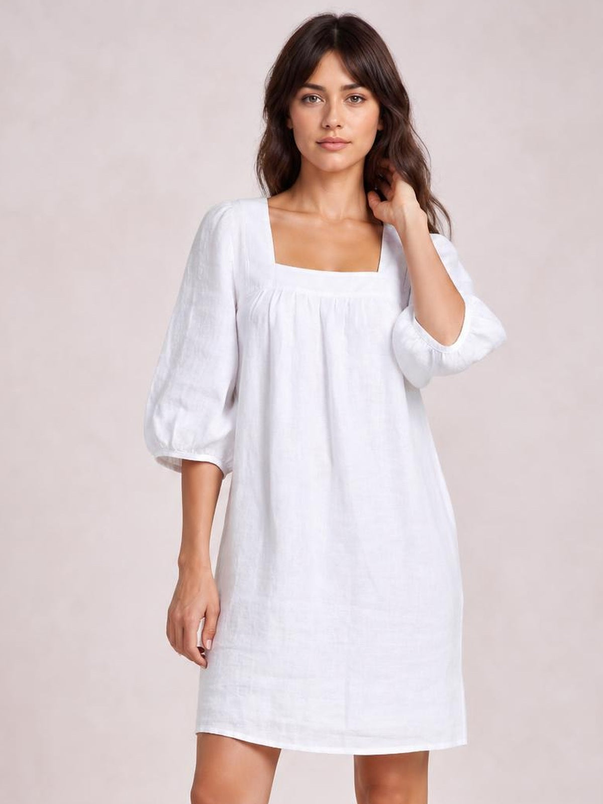 A model poses in a relaxed white square-neck mini dress with voluminous puff sleeves, a loose straight silhouette, and visible seam detailing.
