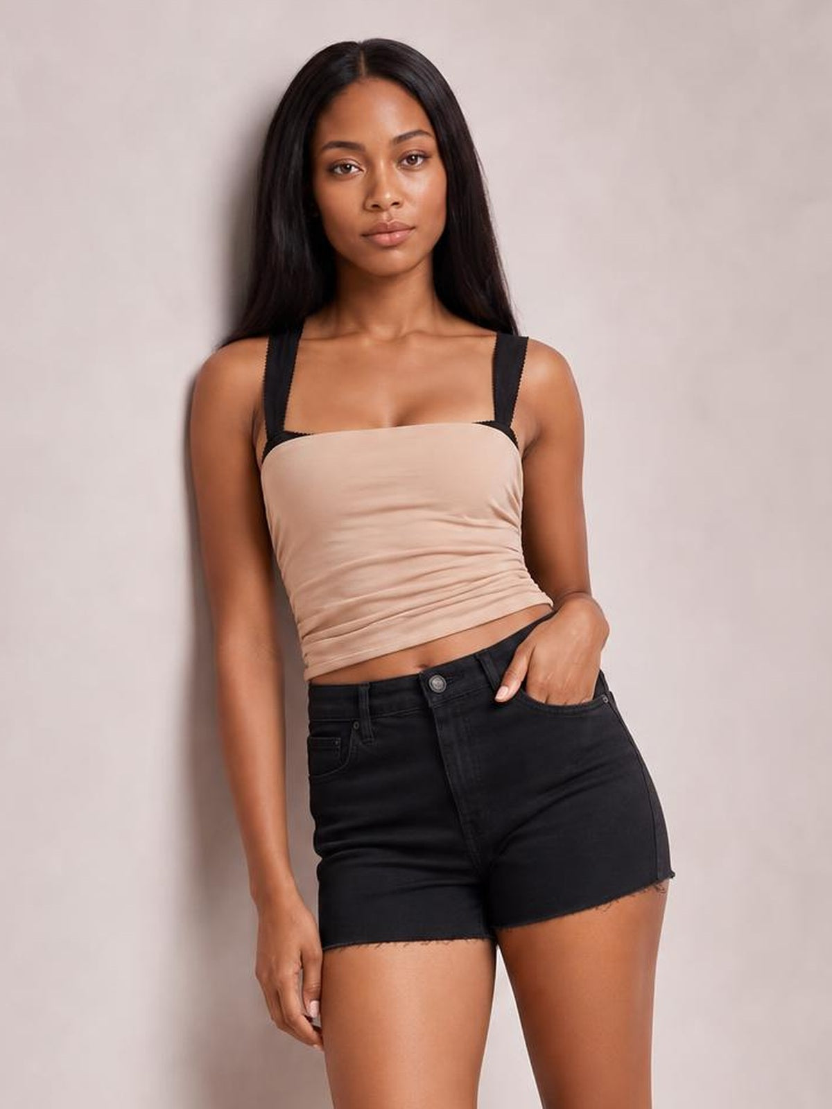 Model wears a beige square neck wide strap cami with a fitted, slightly ruched silhouette, posing with one hand in her shorts pocket.