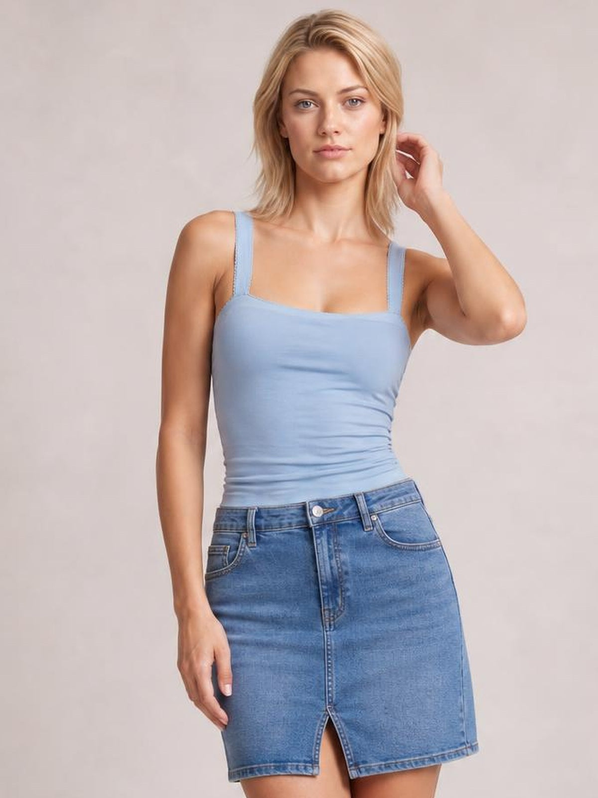 Model poses in a light blue square neck wide strap cami with a fitted, slightly ruched silhouette and opaque stretch construction.