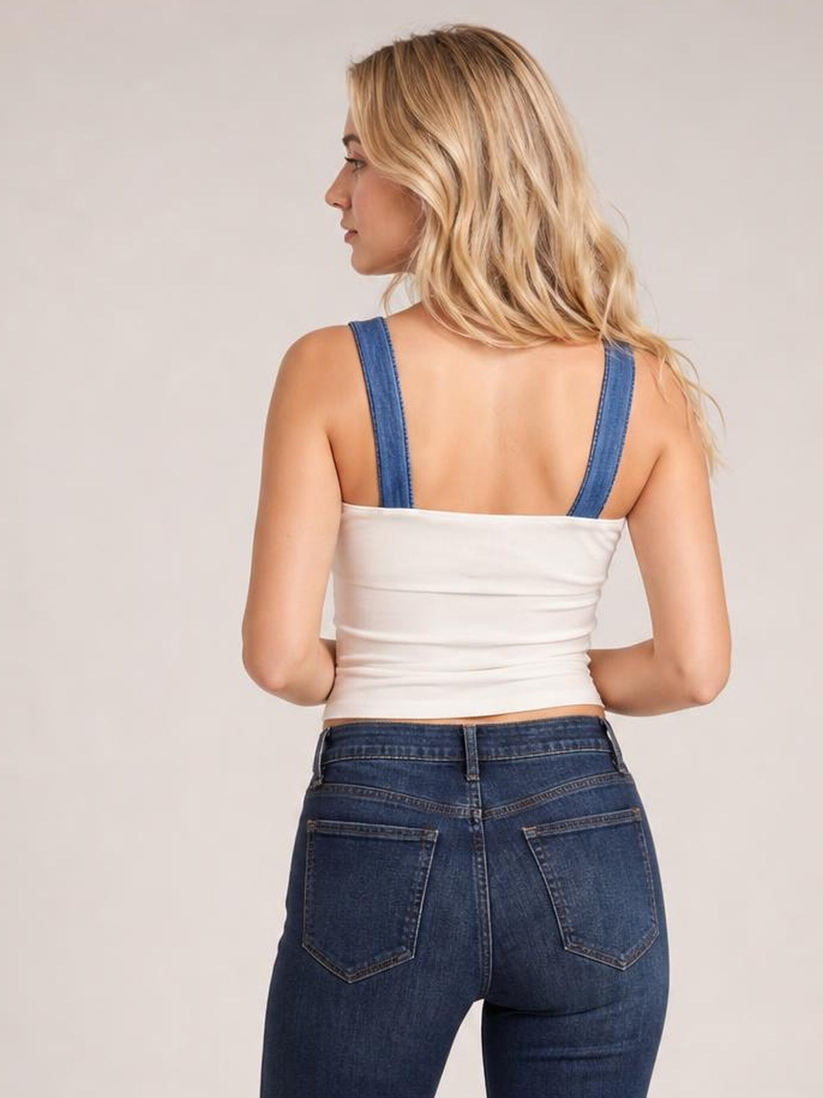 Model viewed from behind wears a white square neck cami with wide straps, a fitted slightly stretchy silhouette, and a cropped hem with subtle ruching.