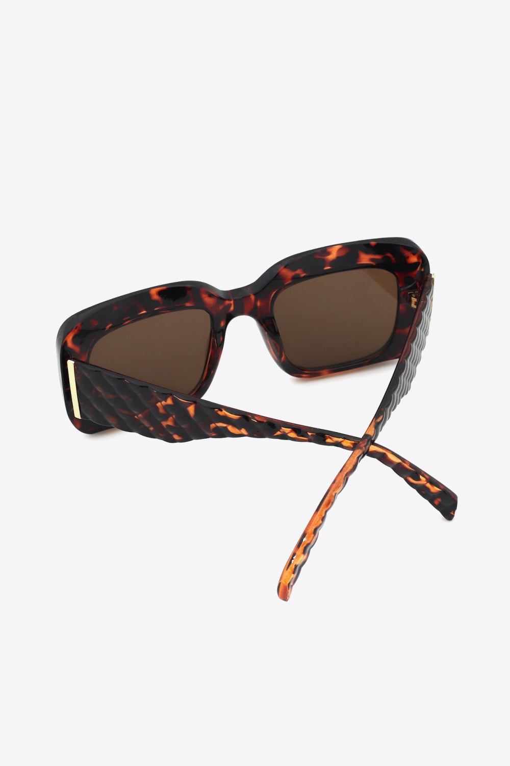 Square polycarbonate sunglasses feature a bold tortoiseshell frame, brown lenses, structured square shape, and crossed temples with a subtle gold hinge accent.