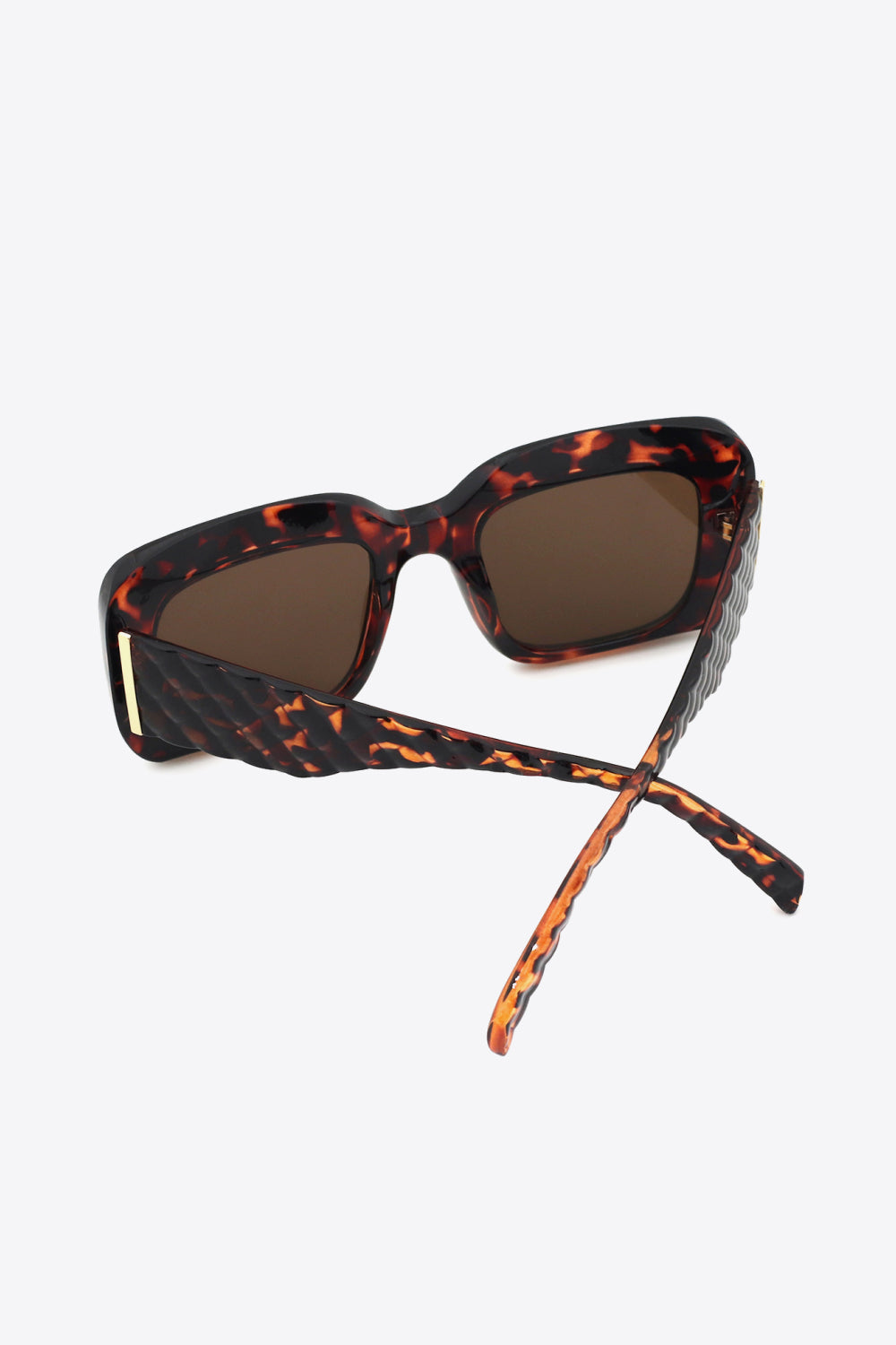 Square polycarbonate sunglasses feature a bold tortoiseshell frame, brown lenses, structured square shape, and crossed temples with a subtle gold hinge accent.