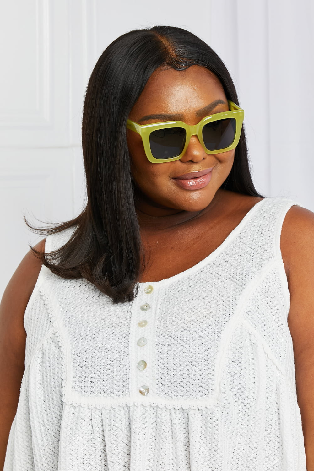 A model turns slightly to showcase bold square sunglasses with a vivid neon yellow acetate frame, structured silhouette, and dark TAC polarized lenses.