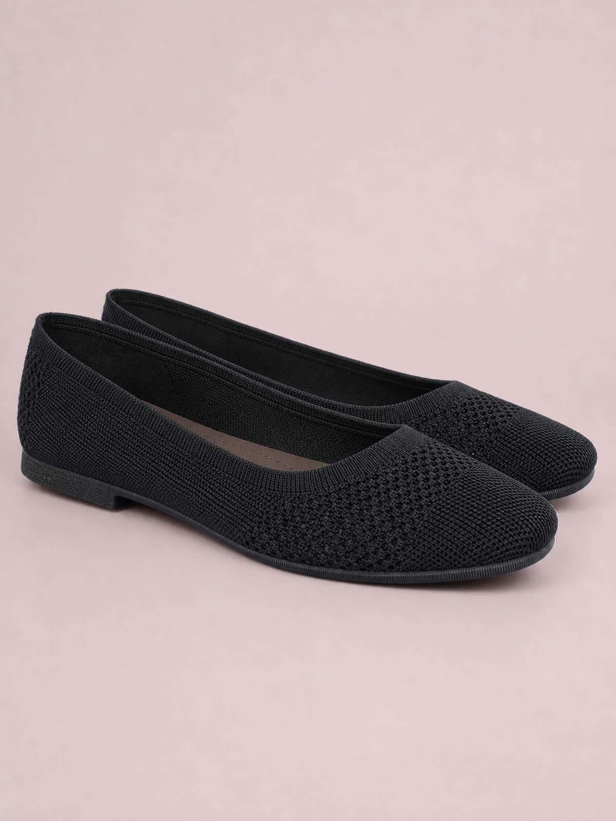 Black solid-color mesh slip-on flats feature a square toe, textured knit construction, low profile, and a slim rubber sole.