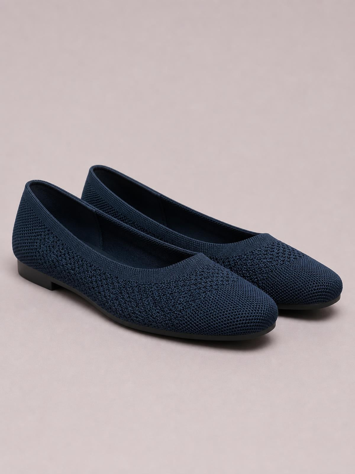 Pair of solid navy mesh slip-ons with square toes, low-cut openings, textured knit construction, and flat black rubber soles.