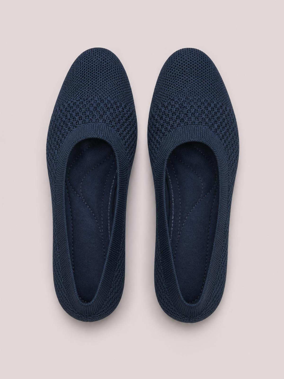 Pair of dark navy solid-color mesh slip-ons with square toes, knitted uppers, cushioned insoles, and flat rubber soles shown from above.