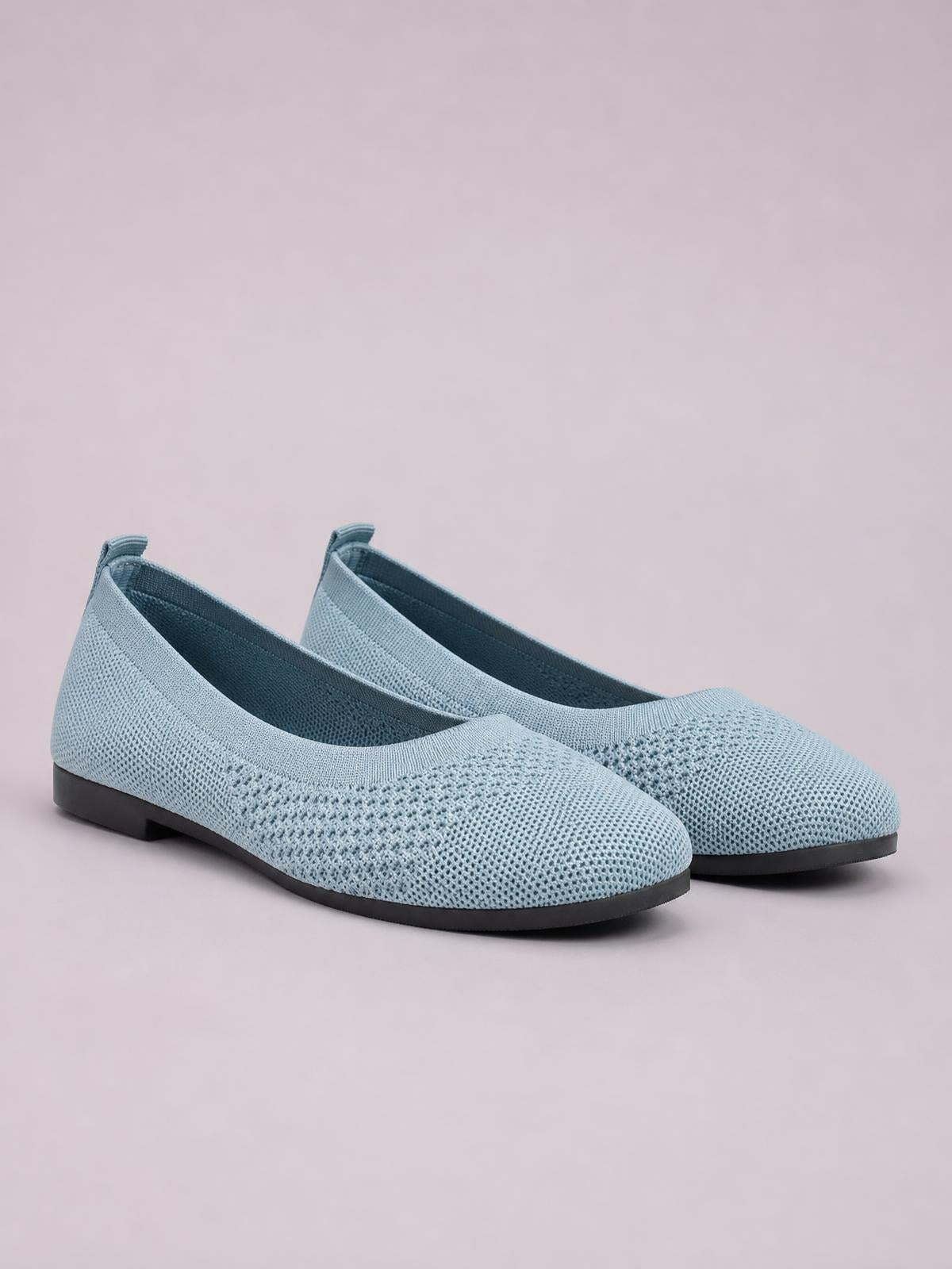 Light blue mesh slip-on flats with a square toe, low black rubber soles, rounded silhouette, and textured woven construction.