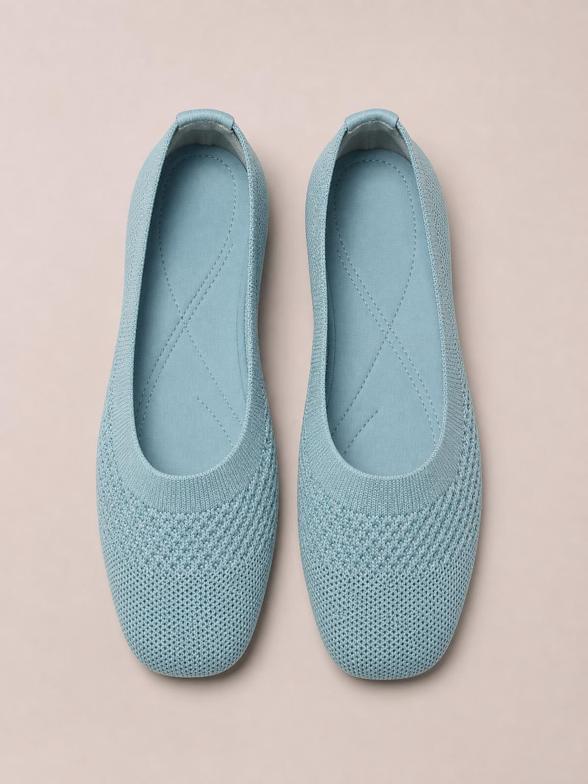 A pair of solid blue mesh slip-ons with square toes, low flat soles, cushioned insoles, and textured woven uppers.