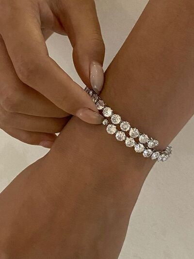 A visible hand fastens a stainless steel inlaid zircon bracelet featuring multiple rows of sparkling round stones in a slim, curved wrist-hugging design.