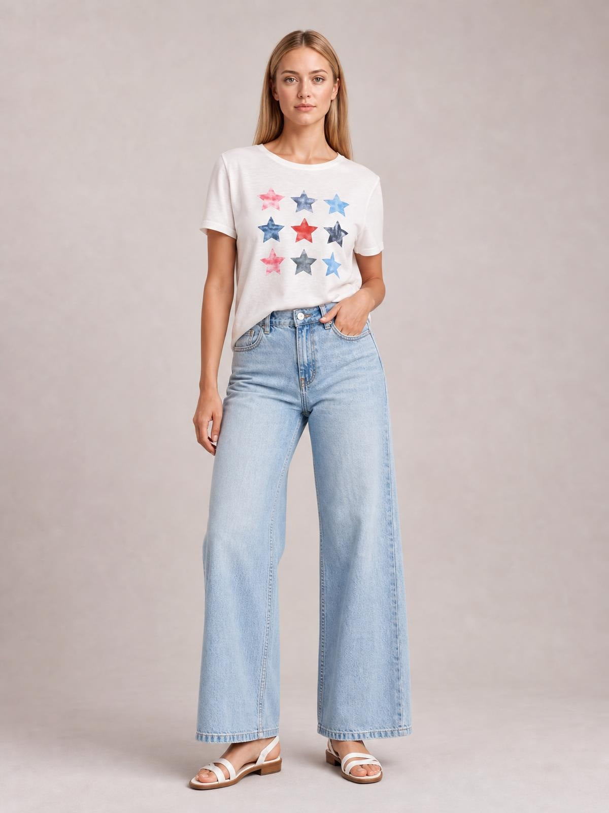Model wearing a white star-print round neck short sleeve T-shirt with a relaxed silhouette, tucked into high-waisted wide-leg jeans.