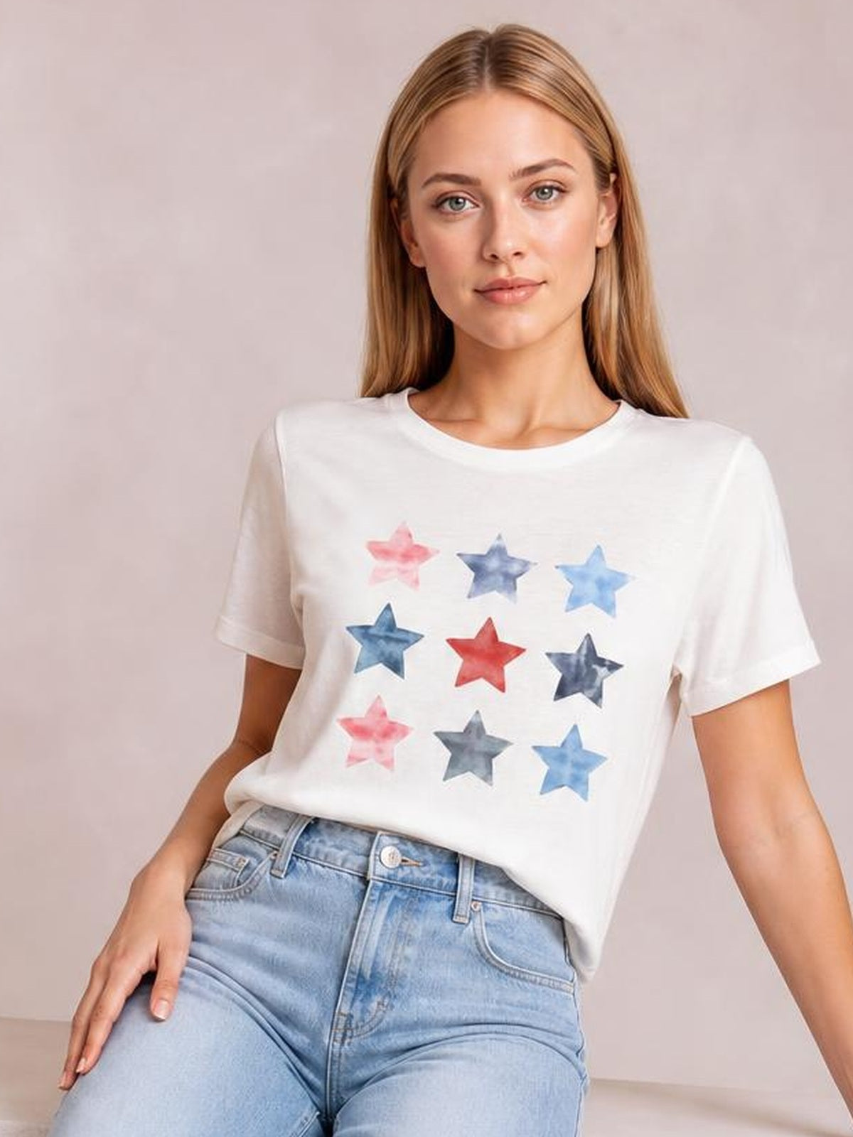 Model poses in a white round-neck short-sleeve T-shirt with a relaxed silhouette and colorful star graphic, paired with light-wash jeans.